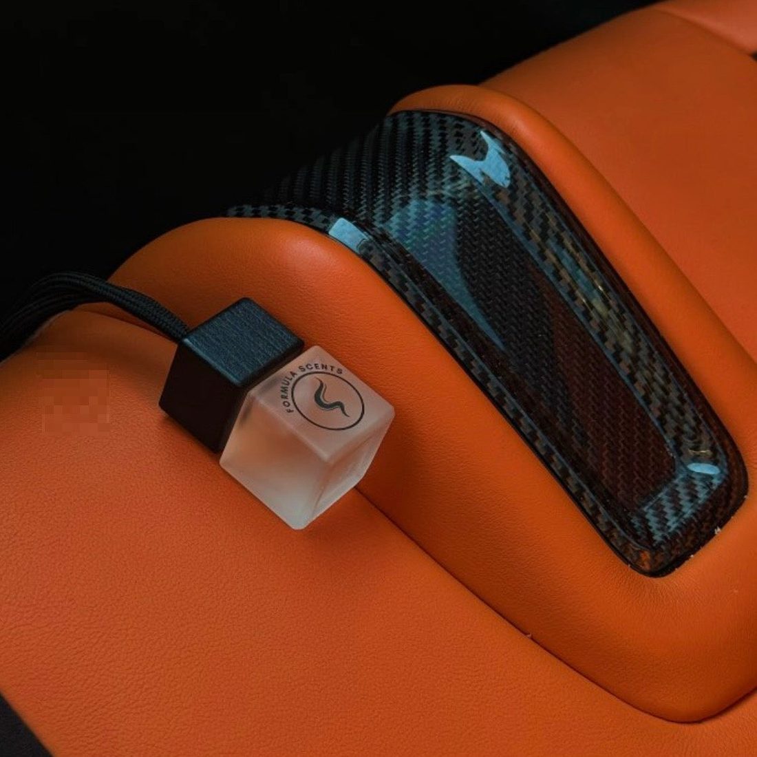 Flacon Formula Scents givré sur un accoudoir de cuir orange et carbone