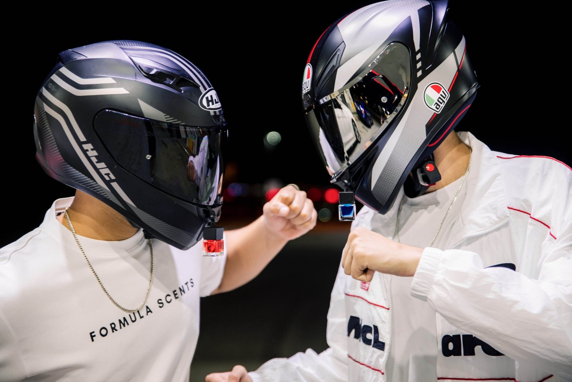 Les deux fondateurs de Formula Scents, casques de course sur la tête et t-shirts Formula Scents, poing contre poing